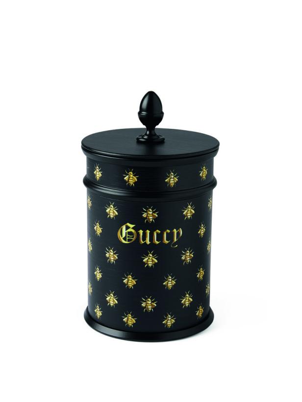 Eine schwarze Dose mit dem goldenen Gucci-Schriftzug und goldenen Bienen.