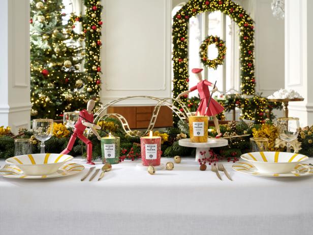 Ein festlich gedeckter Tisch mit „Acqua di Parma“-Kerzen und Weihnachtsdekorationen.
