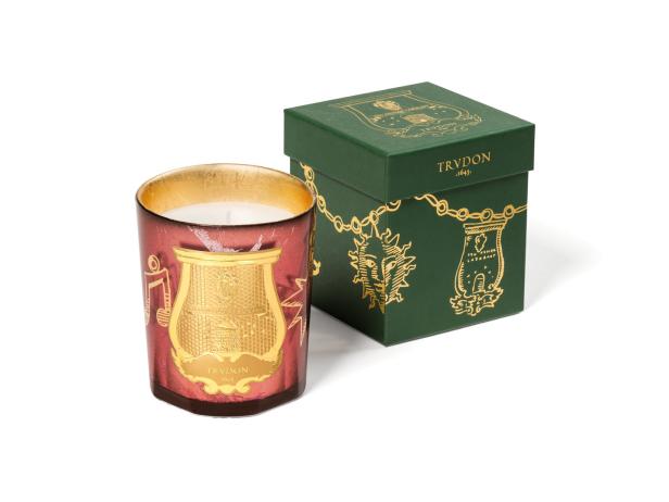 Eine Duftkerze der Marke Trudon neben ihrer grünen Verpackung.