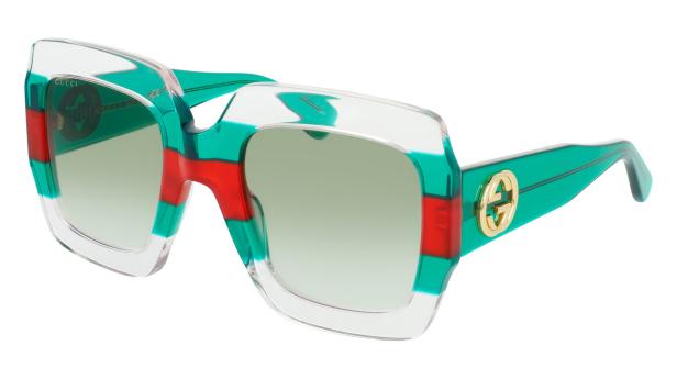 Eine grüne Gucci-Sonnenbrille mit roten Streifen und dem goldenen Gucci-Logo.