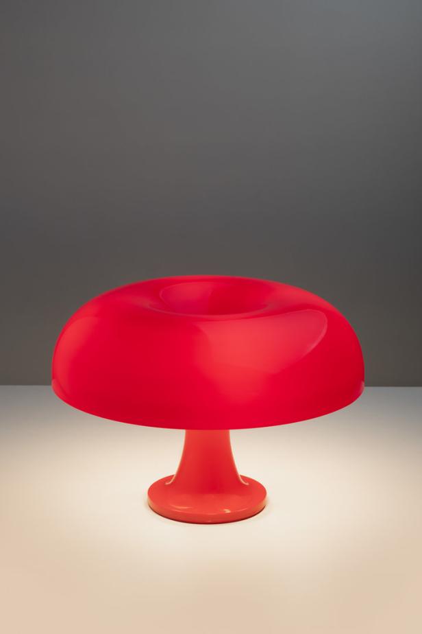 Eine leuchtend rote Tischlampe im Pilzdesign steht auf einer weißen Oberfläche.