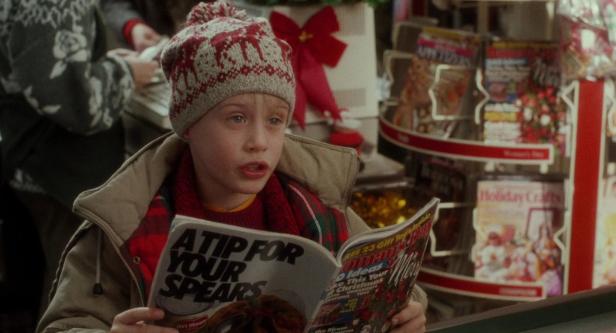 Ein Junge mit Mütze liest eine Zeitschrift vor einem weihnachtlichen Hintergrund.