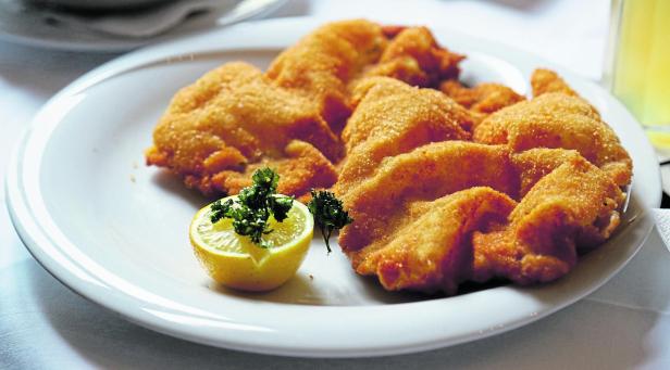 Ein Teller mit Wiener Schnitzel, garniert mit Zitrone und Petersilie.