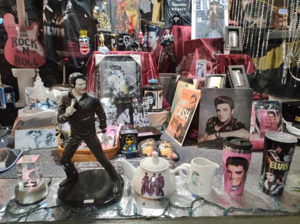Ein Schaufenster voller Elvis Presley-Erinnerungsstücke, darunter eine Statue und diverse Merchandise-Artikel.