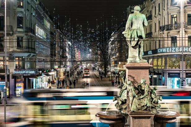Blick auf den beleuchteten Zürcher Bahnhofstrasse mit dem Alfred Escher Denkmal im Vordergrund.