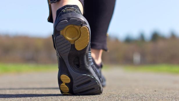 Nahaufnahme der Sohle eines Barfußschuhs beim Gehen auf einer Straße.