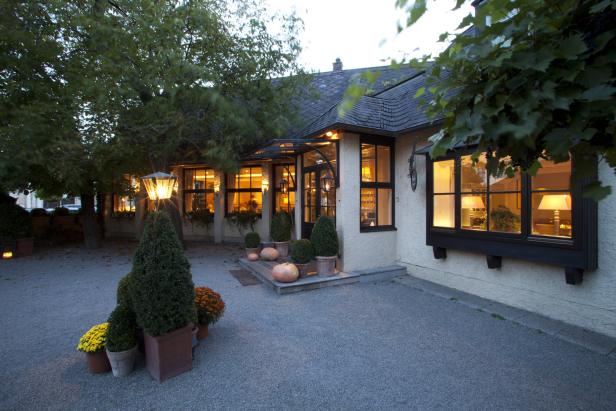 Einladende Fassade eines Restaurants mit herbstlicher Dekoration und warmem Licht.