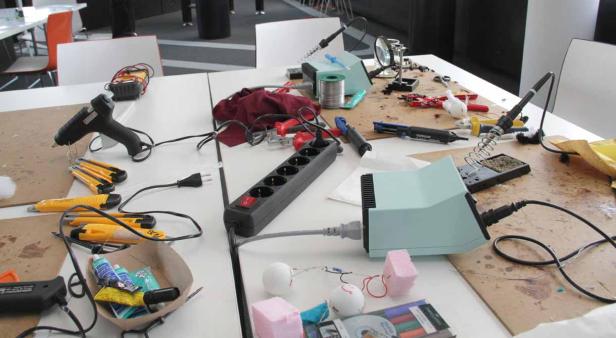 Ein Tisch voller Werkzeuge und Materialien für Bastelarbeiten und Elektronikprojekte.