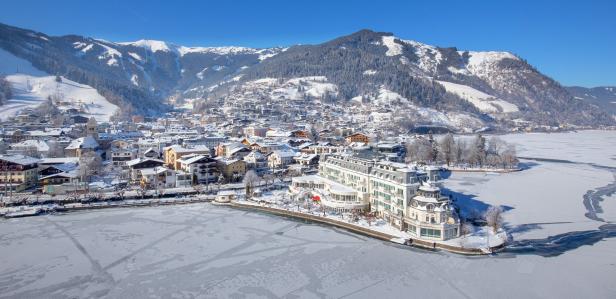 Ein Blick auf Zell am See im Winter mit einem zugefrorenen See und schneebedeckten Bergen im Hintergrund.