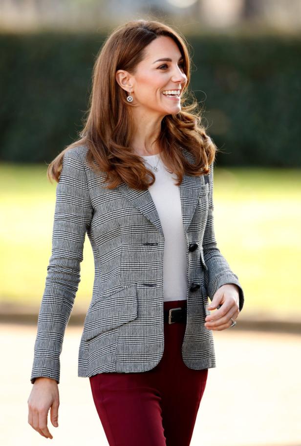 Catherine, Prinzessin von Wales, lächelt in einem karierten Blazer und einer roten Hose.
