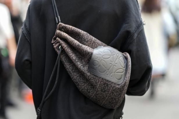 Eine Person trägt eine braune Loewe-Beuteltasche über der Schulter.