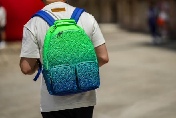 Ein Mann trägt einen grünen und blauen Louis Vuitton Rucksack.