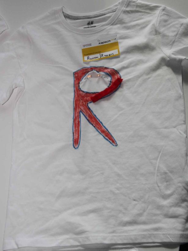 Ein weißes T-Shirt mit einem roten „R“, verziert mit kleinen Lichtern.