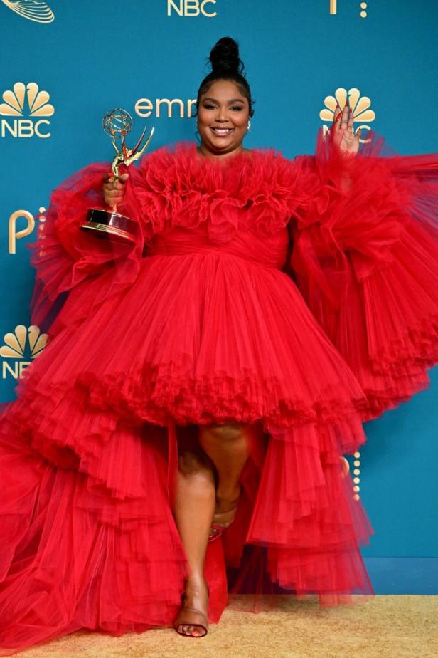 Lizzo in einem roten Rüschenkleid mit einem Emmy-Award in der Hand.