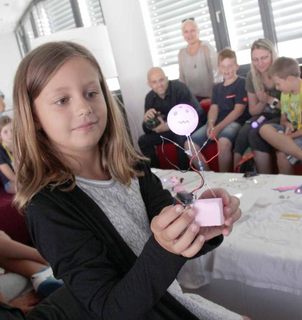 Ein Mädchen hält eine selbstgebaute Figur mit einem leuchtenden Ballon in den Händen.