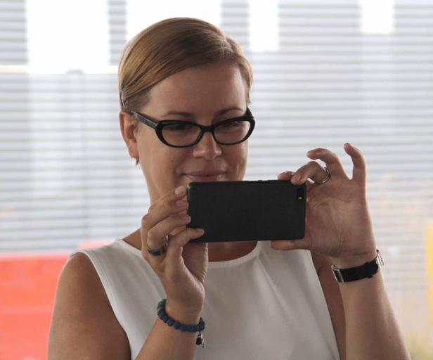Eine Frau mit Brille fotografiert mit ihrem Smartphone.