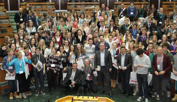 Eine große Gruppe von Jugendlichen und Erwachsenen posiert für ein Foto in einem Auditorium.