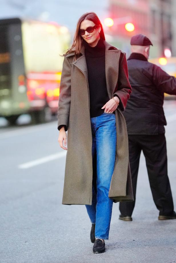 Karlie Kloss geht in einem langen Mantel und Jeans die Straße entlang.