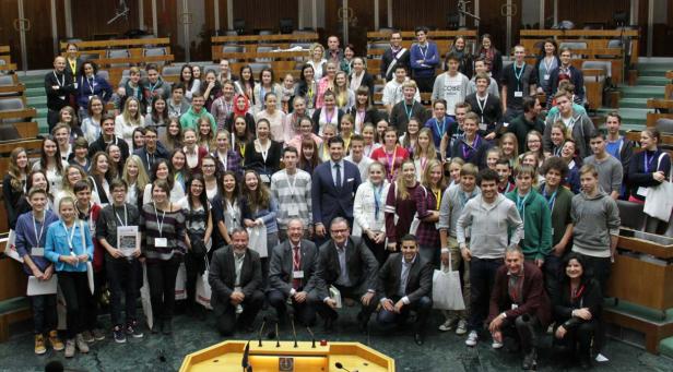 Eine große Gruppe von Menschen posiert im österreichischen Parlament für ein Foto.