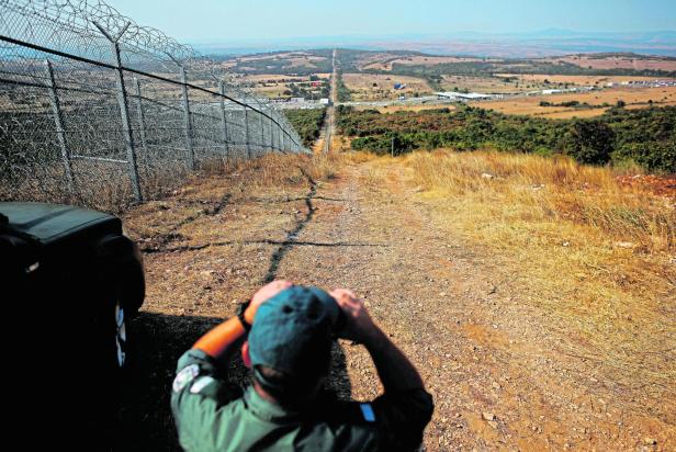 FILE PHOTO: Bulgarian border policeman monitors near the barbed wire fence constructed on the Bulgarian-Turkish border