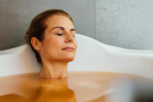 Eine Frau entspannt mit geschlossenen Augen in einer Badewanne.