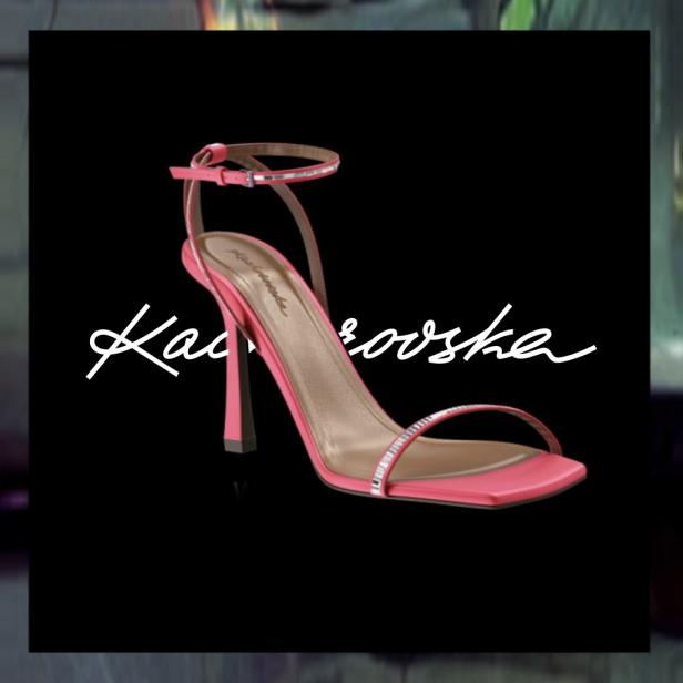 Ein pinkfarbener, hochhackiger Damensandalette mit Strassdetails vor schwarzem Hintergrund.