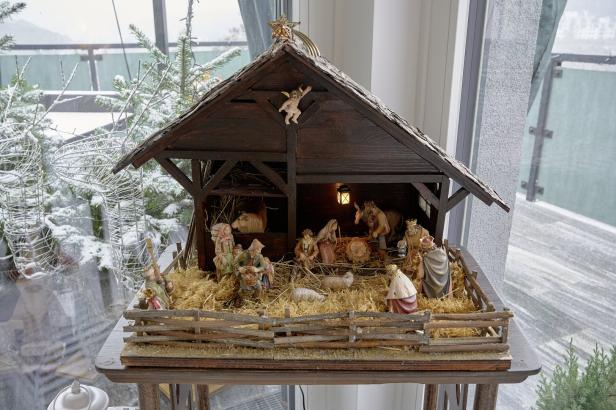 Eine Weihnachtskrippe mit Figuren in einem Stall vor einem Fenster.