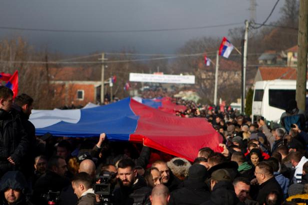 Local Serbs carry a giant Serbian flag as they protest against the government near a roadblock in Rudare, Kosovo