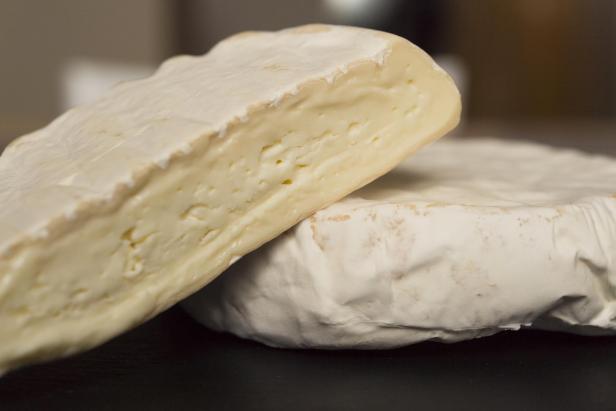 Zwei Stücke Camembert-Käse liegen übereinander.