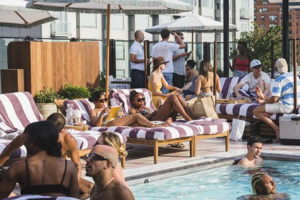Menschen entspannen sich an einem sonnigen Tag am Pool auf Liegen.