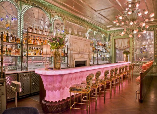 Eine luxuriöse Bar mit rosa Onyx-Theke, floralen Stühlen und üppiger Dekoration.