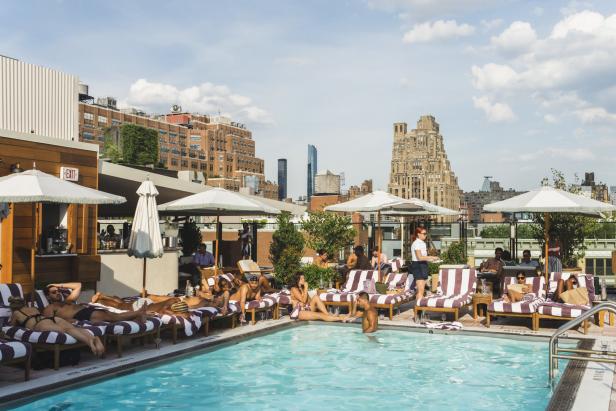 Menschen entspannen am Pool auf dem Dach eines Hotels in New York.