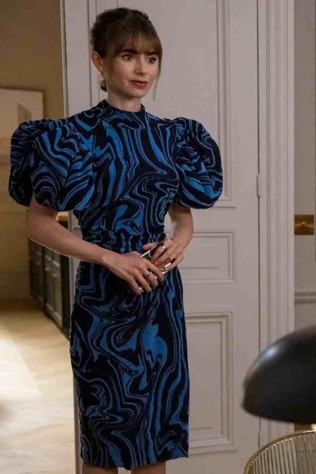 Lily Collins trägt ein blau-schwarz gemustertes Kleid.