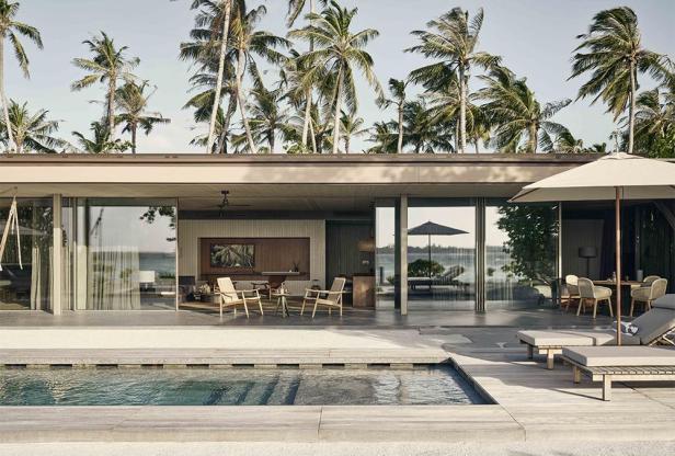 Eine Villa mit Pool auf den Malediven, umgeben von Palmen.