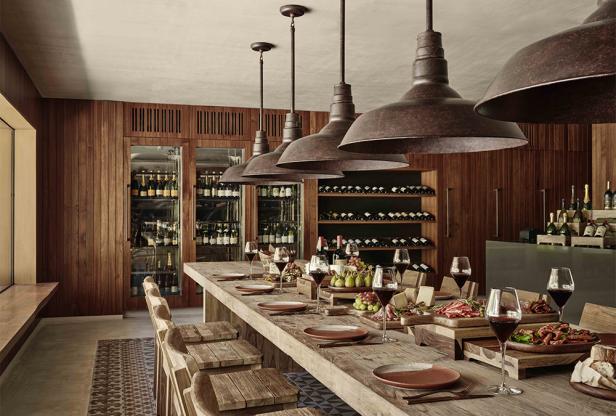 Ein langer Holztisch ist mit Speisen und Getränken für eine Weinprobe gedeckt.