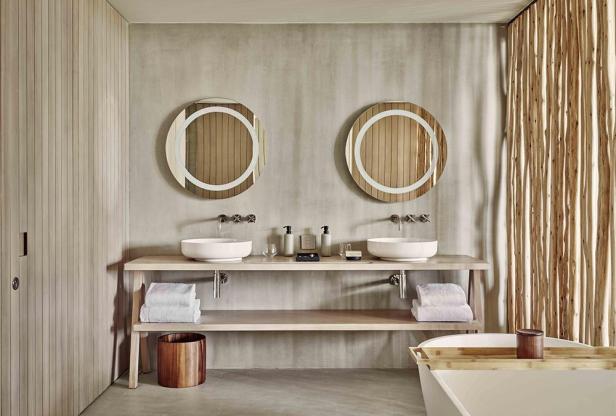 Ein Badezimmer mit zwei runden Spiegeln über Waschbecken auf einem Holztisch.