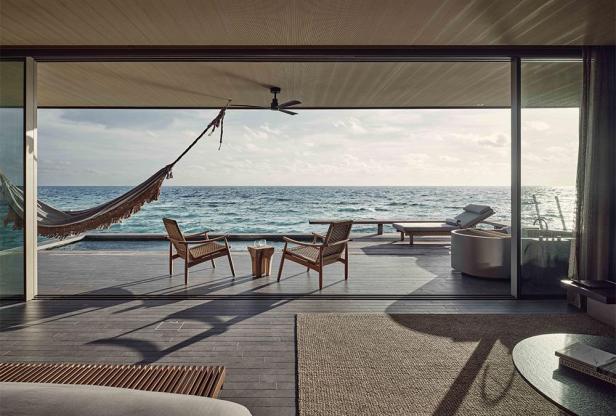 Blick aus einer Villa auf den Malediven auf das Meer mit Hängematte und Liegestühlen.
