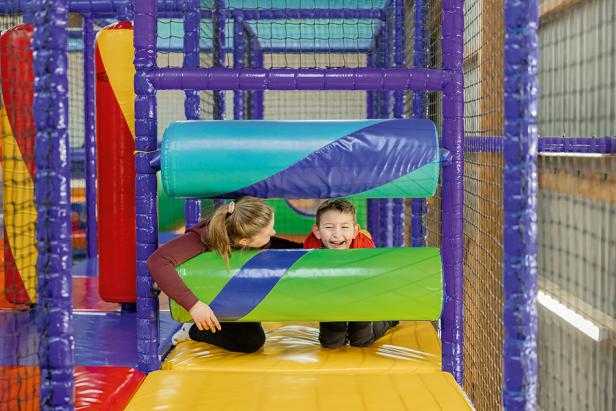 Ein Mädchen und ein Junge spielen in einem bunten Indoor-Spielplatz.