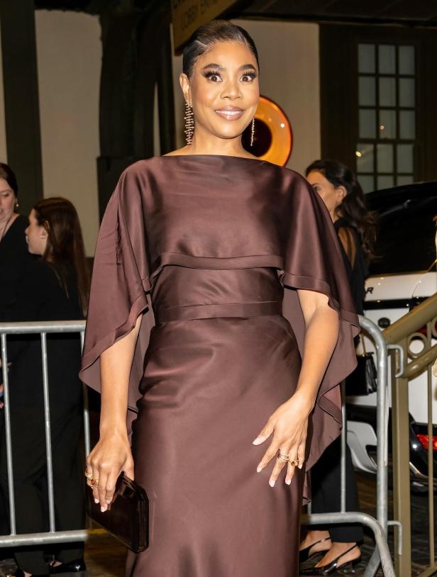 Regina Hall in einem braunen Kleid mit Cape-Ärmeln und goldenen Ohrringen.