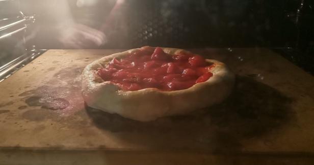 Eine Pizza mit Tomatensoße wird im Ofen gebacken.