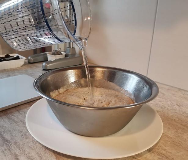 Wasser wird in eine Schüssel mit Teig gegossen.