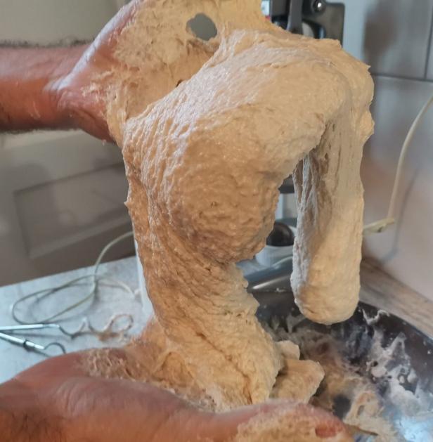 Ein Mann hält einen großen Klumpen Teig in seinen Händen.