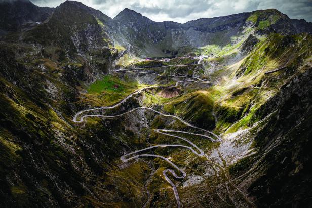 Eine kurvenreiche Straße schlängelt sich durch eine bergige Landschaft.