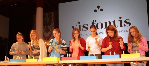 Eine Gruppe junger Frauen spielt auf einem Tischglockenspiel vor einem Publikum.