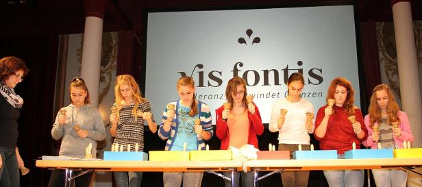 Eine Gruppe junger Frauen spielt Handglocken vor einem Publikum.