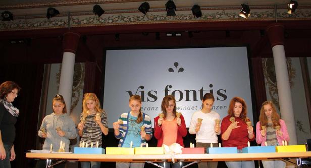 Eine Gruppe junger Frauen spielt auf einer Bühne mit Handglocken.