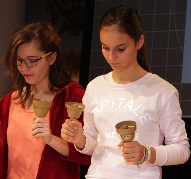 Zwei junge Frauen spielen Handglocken.