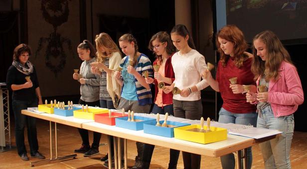 Eine Gruppe junger Frauen spielt Handglocken vor Publikum.