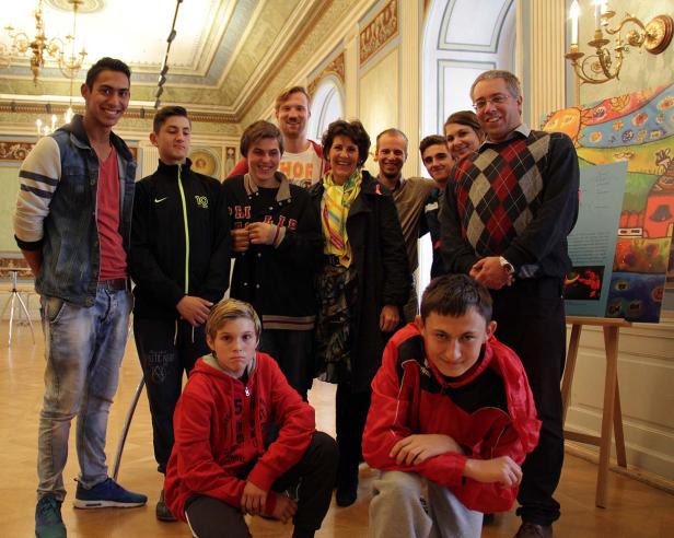 Eine Gruppe von Menschen posiert in einem Raum mit einem farbenfrohen Kunstwerk.