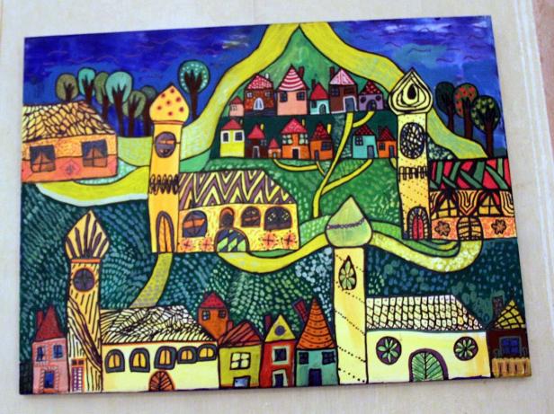 Ein farbenfrohes Gemälde einer Stadt mit Türmen und Häusern unter einem blauen Himmel.